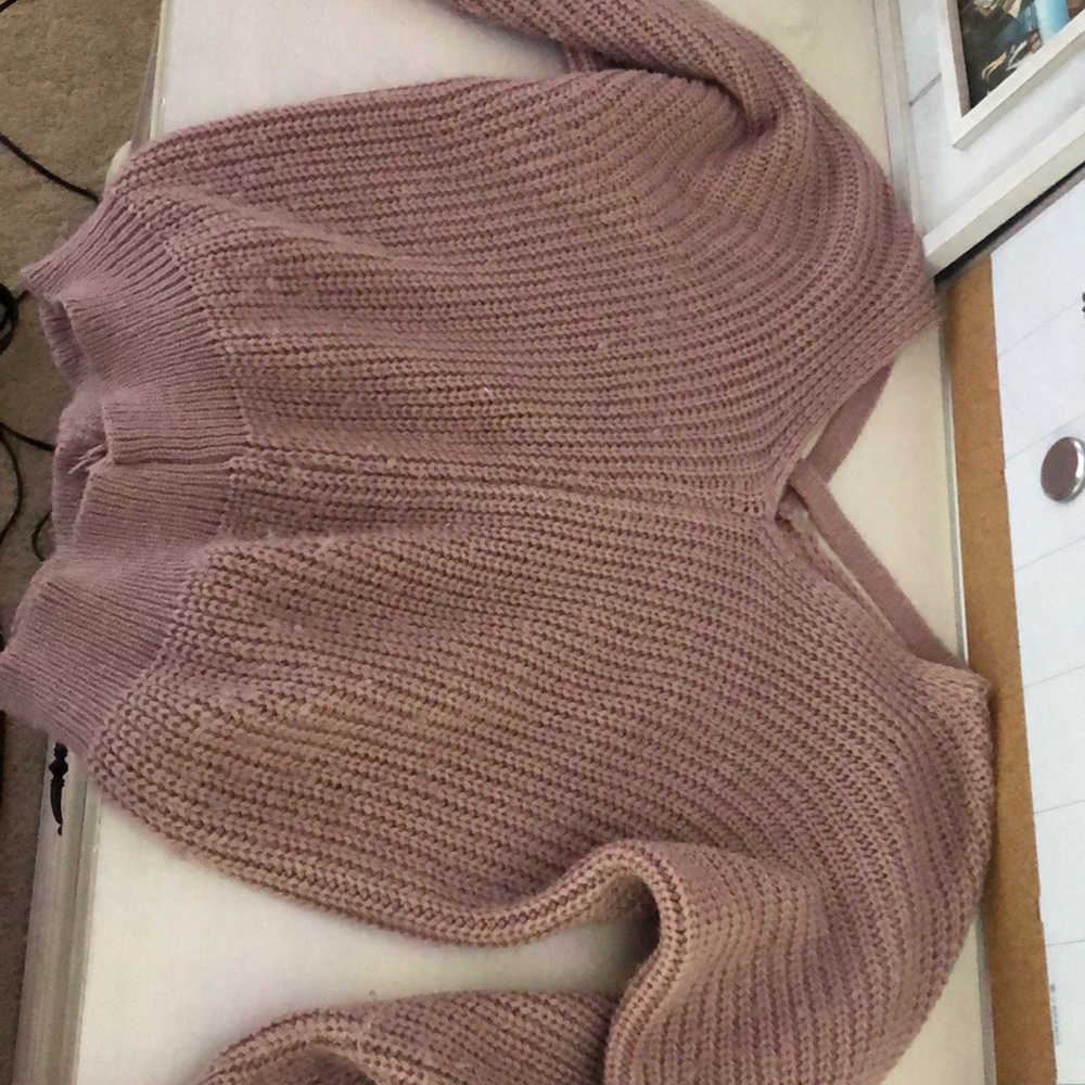a pink knitted sweater with cross backing